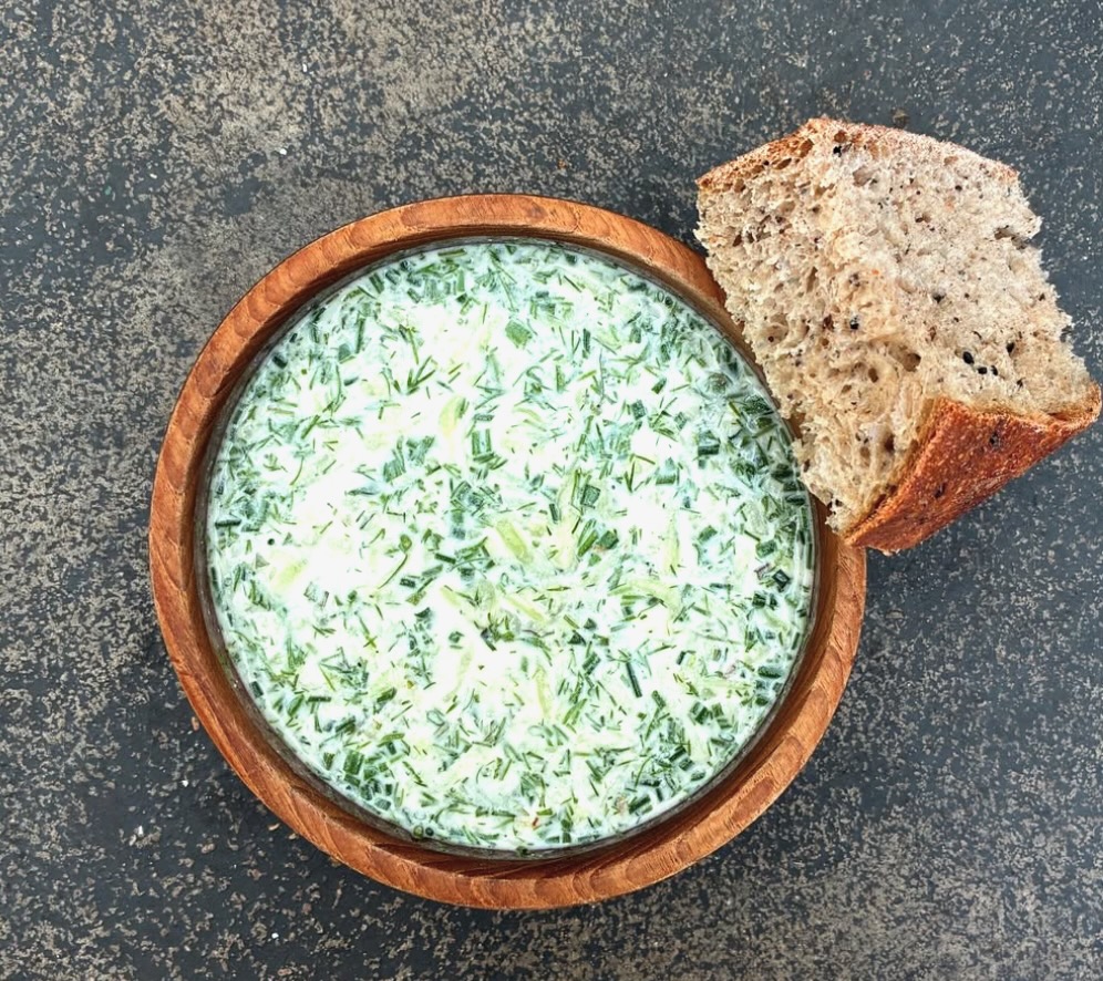 A cucumber soup from Apteka with a piece of bread beside it.