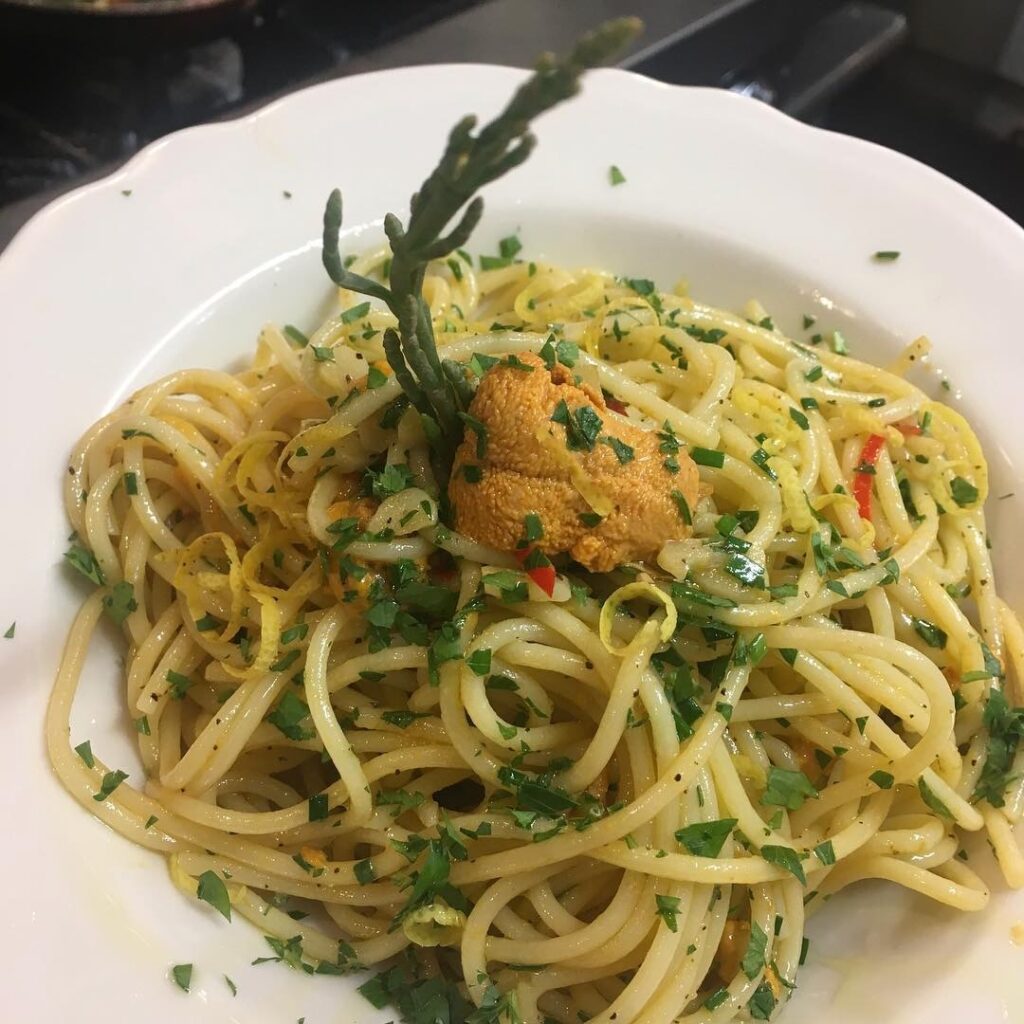 A plate of pasta from Dish in a white plate with herbs on it.