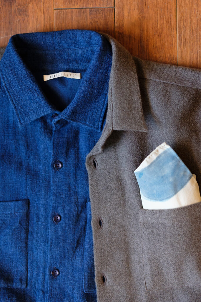 On a wooden surface ou see the top of a button up, the left side blue, the right side dark grey. blue design trends