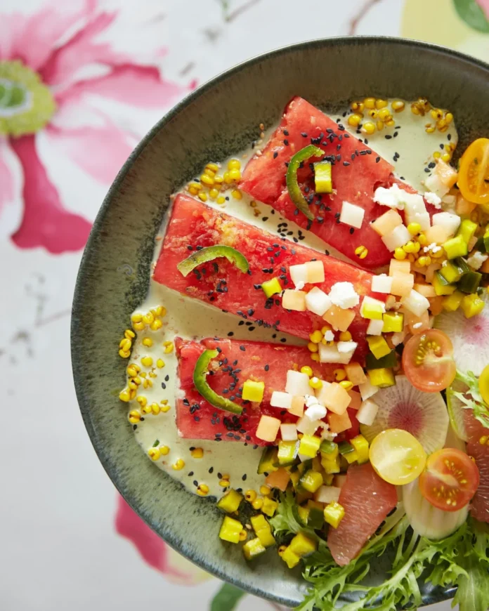 An above shot of a bowl filled with brightly colored fruit, making up a watermelon steak salad.