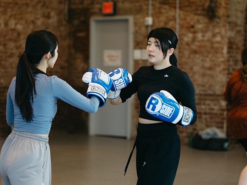 Two people box at a wellness day event.
