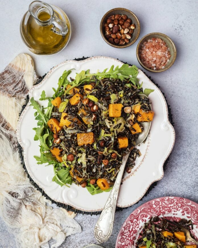 Wild Rice with Butternut Squash, Raisins and Hazelnuts A plate of wild rice with butternut squash, raisins, and hazelnuts, served over a bed of arugula, next to a bottle of olive oil and bowls of salt and hazelnuts.