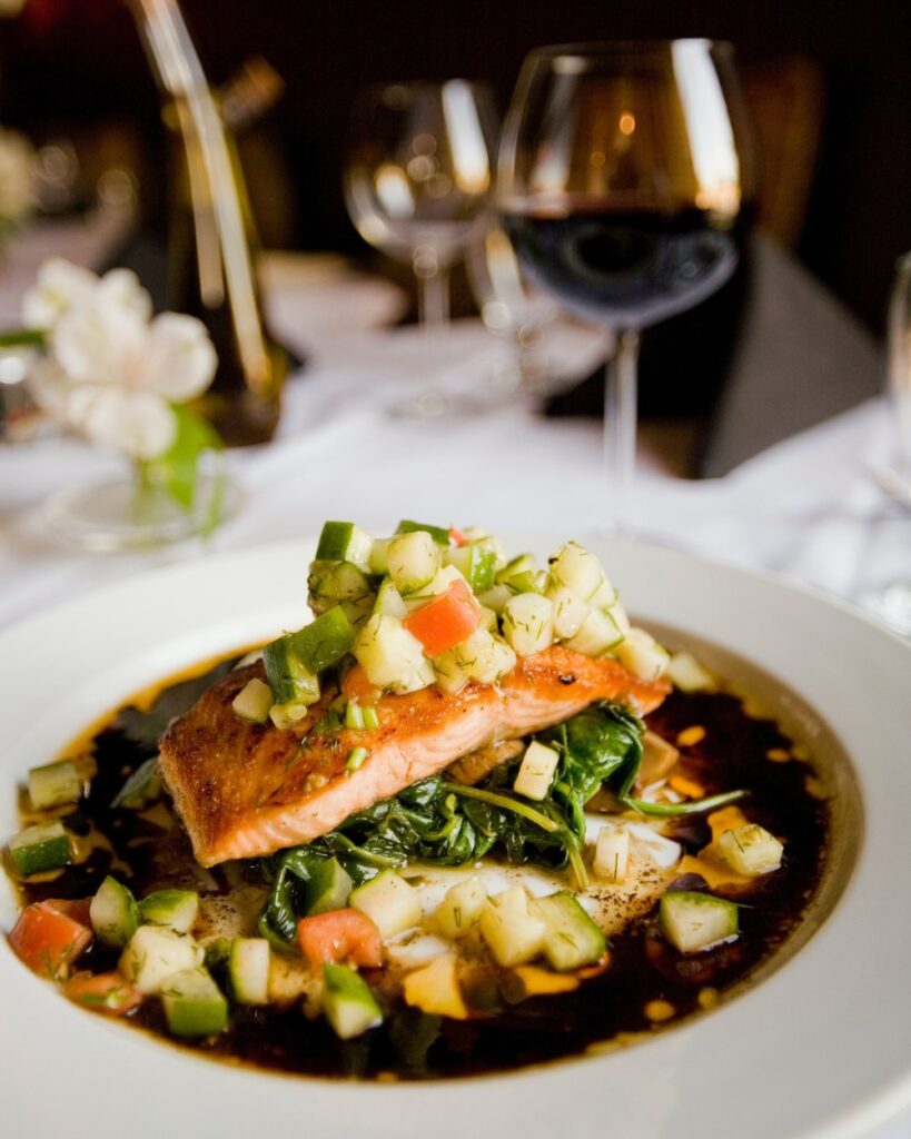 A roasted salmon sits on a bed of spinach, zucchini, and dill relish.