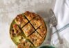 Breakfast Casserole with Caramelized Onions, Dates and Gruyere A table set with a delicious breakfast casserole, complemented by bread, figs, and an assortment of fresh fruits for sharing.