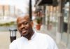 Café Momentum’s Chef Shares His Favorite Pittsburgh Breakfast Spots Chef Robert Carter at Pittsburgh breakfast spot Cafe Momentum leans against a railing in a white chef's coat.