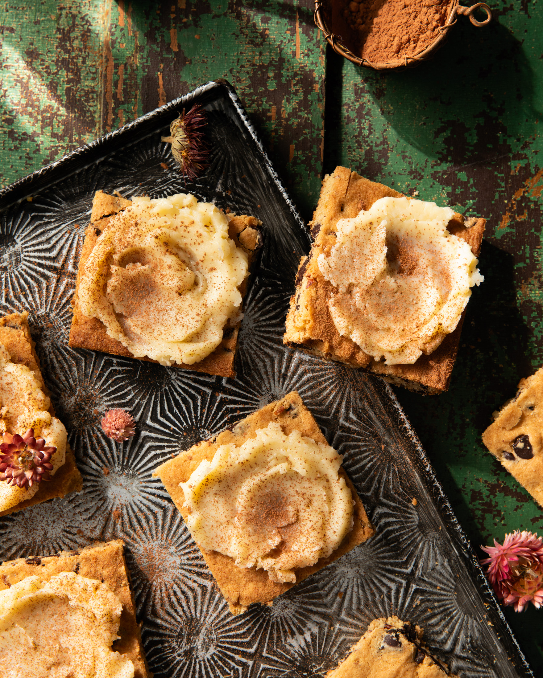 Dark Rum Blondies with butter spread on a serving plate with wild flowers scattered around.