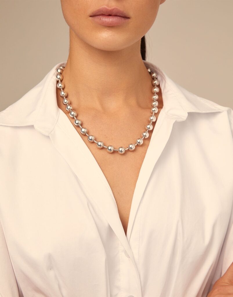 A woman with a white blouse and necklace.