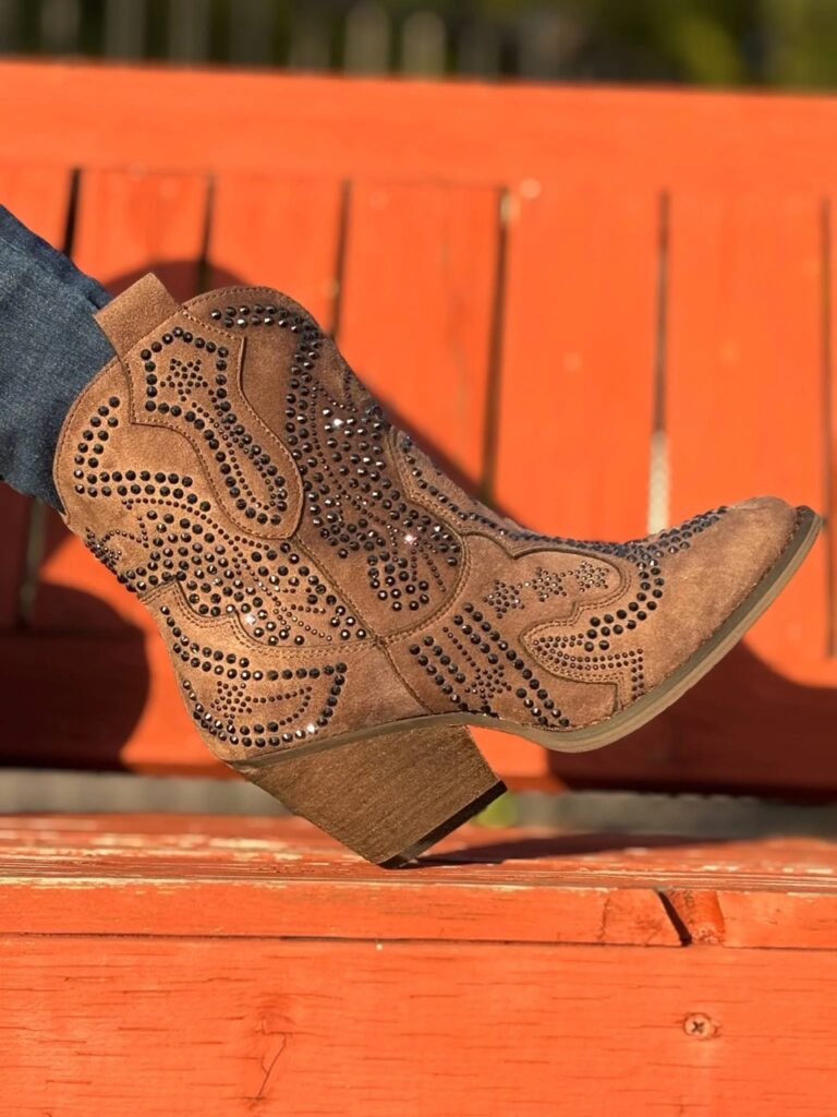 A cowboy boot on an orange bench.