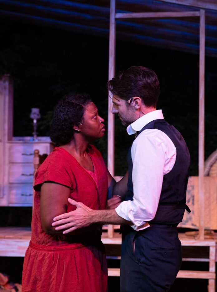 A man and a woman in a red dress stand together on a theater stage in pittsburgh.