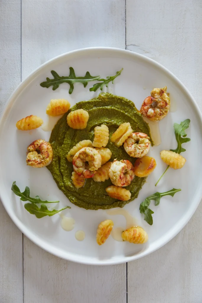 An above shot of a plate of Gnocchi with Arugula Pesto and Shrimp.