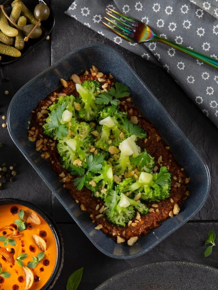 Grilled Broccoli with Romesco A plate of grilled broccoli with romesco sauce, topped with parsley and chopped nuts, with a small bowl of capers.