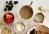 Carrot Cake Baked Oatmeal A breakfast bowl with baked carrot cake oatmeal, surrounded by small bowls of toppings, including strawberries, blueberries, blackberries, shredded coconut, and brown sugar.