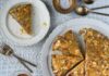 Luscious Almond Cake with Grand Marnier A glazed almond cake topped with sliced almonds and orange zest, with two slices on separate plates and a glass of amber liquid, all on a patterned white tablecloth.