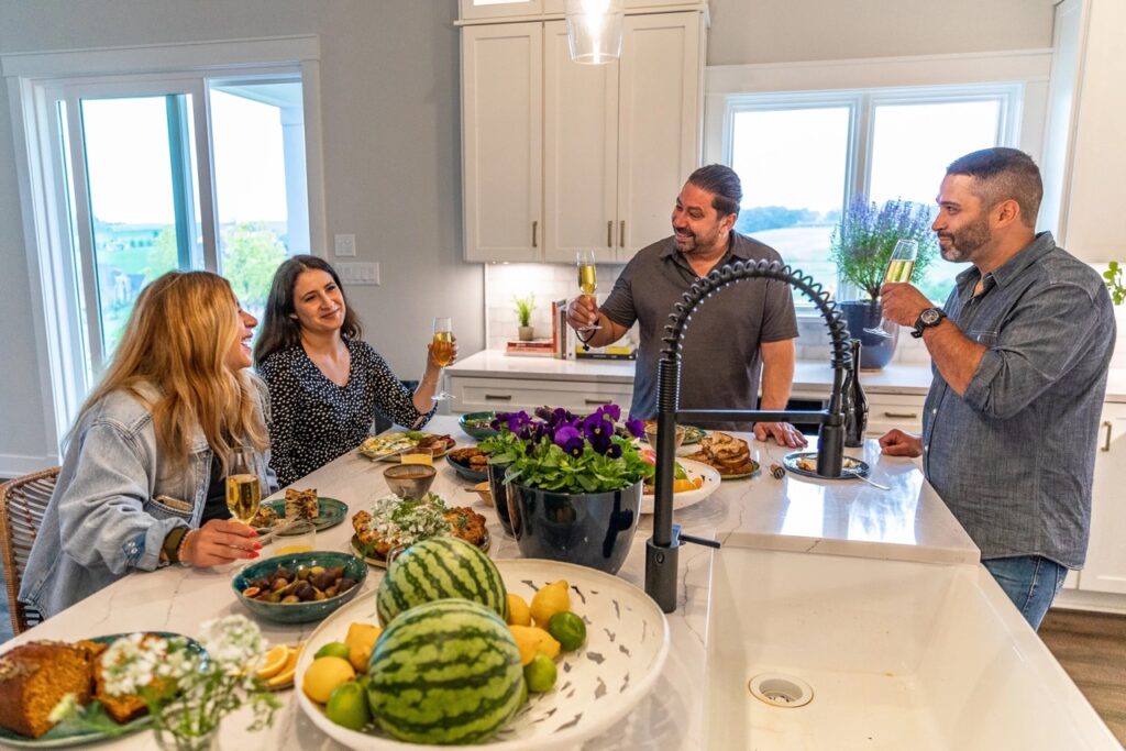 A group of people talk around a kitchen island.