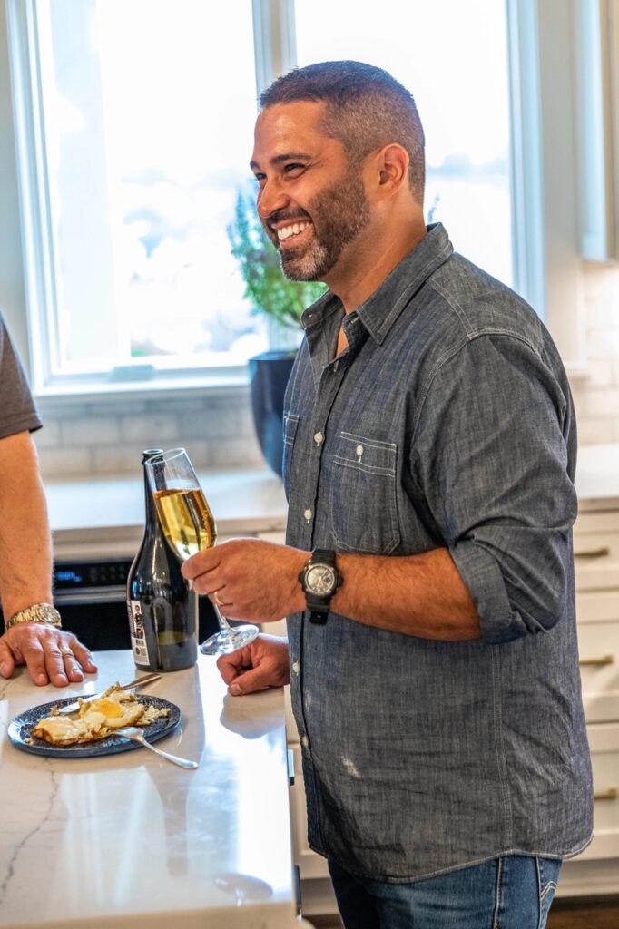 A man smiles with a champagne glass in his hand. 