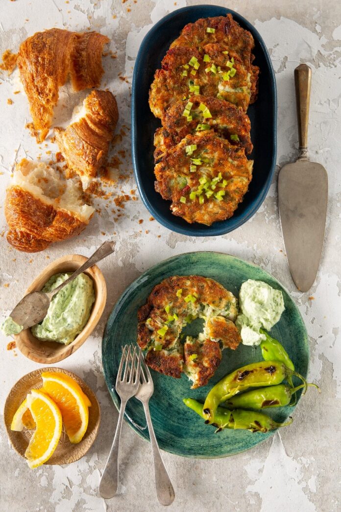 Mediterra Kohlrabi Fritters A platter of golden brown kohlrabi and leek fritters, with a bowl of yogurt sauce, and a croissant.
