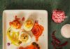 Veda Sankaran’s Indian Fusion Recipes A white plate holds an array of chicken tikka deviled eggs covered in an orange chili oil.
