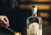 Pittsburgh Events: Your Guide to October 20-26 A person places a garnish on a cocktail glass as a bottle of whiskey sits behind it on a marble counter.