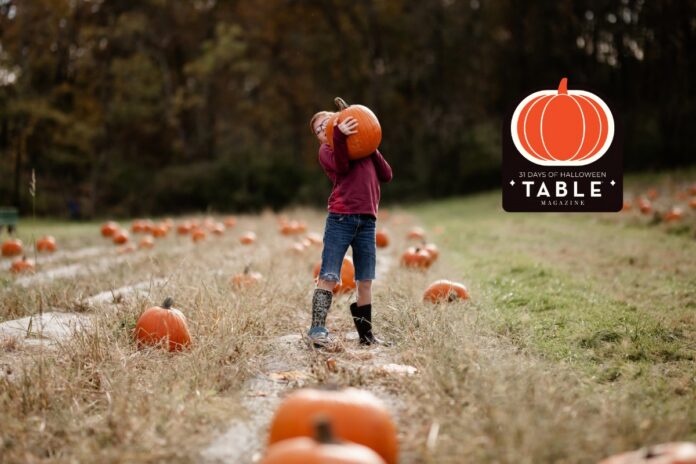 Pumpkin Patches Halloween 31 Days Logo TABLE Magazine Child carrying a large pumpkin at a Pittsburgh pumpkin patch.