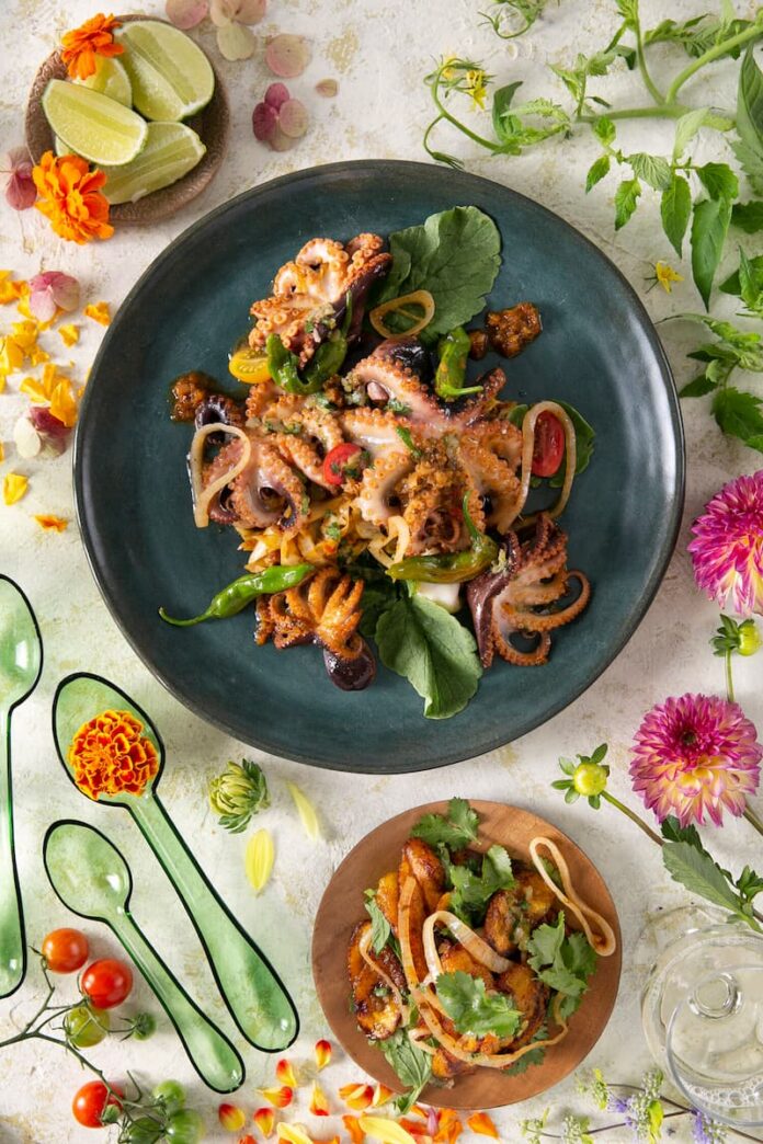 Sauteed Octopus with Criolla Sauce Sauteed Octopus with Criolla Sauce served on a dark green plate with a side dish.