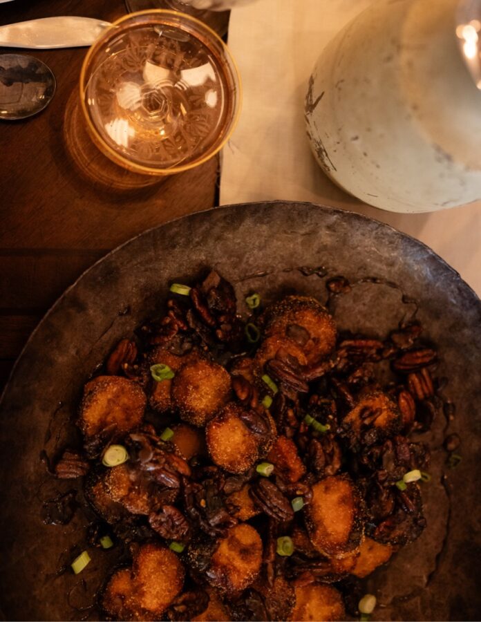Sweet Potato Rounds with Bacon & Pecan Glaze Sweet potato rounds sit on a brown plate beside a drink on the dinner table.