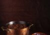 Texas Chili Texas chili sits in a large pot with a bowl of chili in front of it topped with cheese and a bowl of red onions beside it.