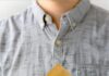 Black Truffle Popcorn A person in a gray shirt holding a brown paper cone filled with popcorn, featuring a top-down view of the popcorn kernels.
