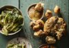 Recipes for Seasonal Ramps and Greens A green picnic table with a Caesar salad, garlic knots, and beans and greens bowl on top.