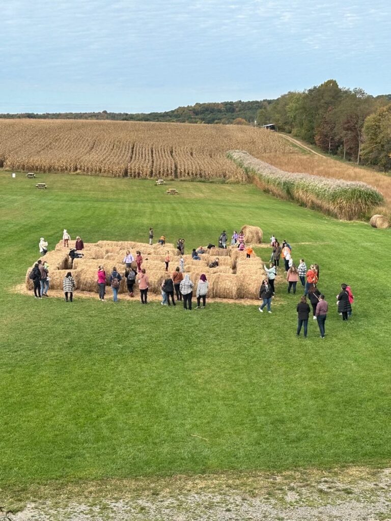 People explore a hay bale maze at a Pittsburgh pumpkin patch in autumn.