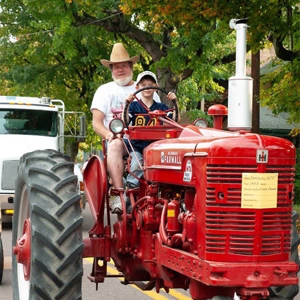Man and boy on red vintage tractor at a Pittsburgh fall festival