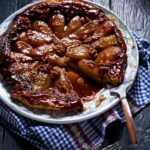 A pear crostata with maple syrup sitting on a pattern plate.