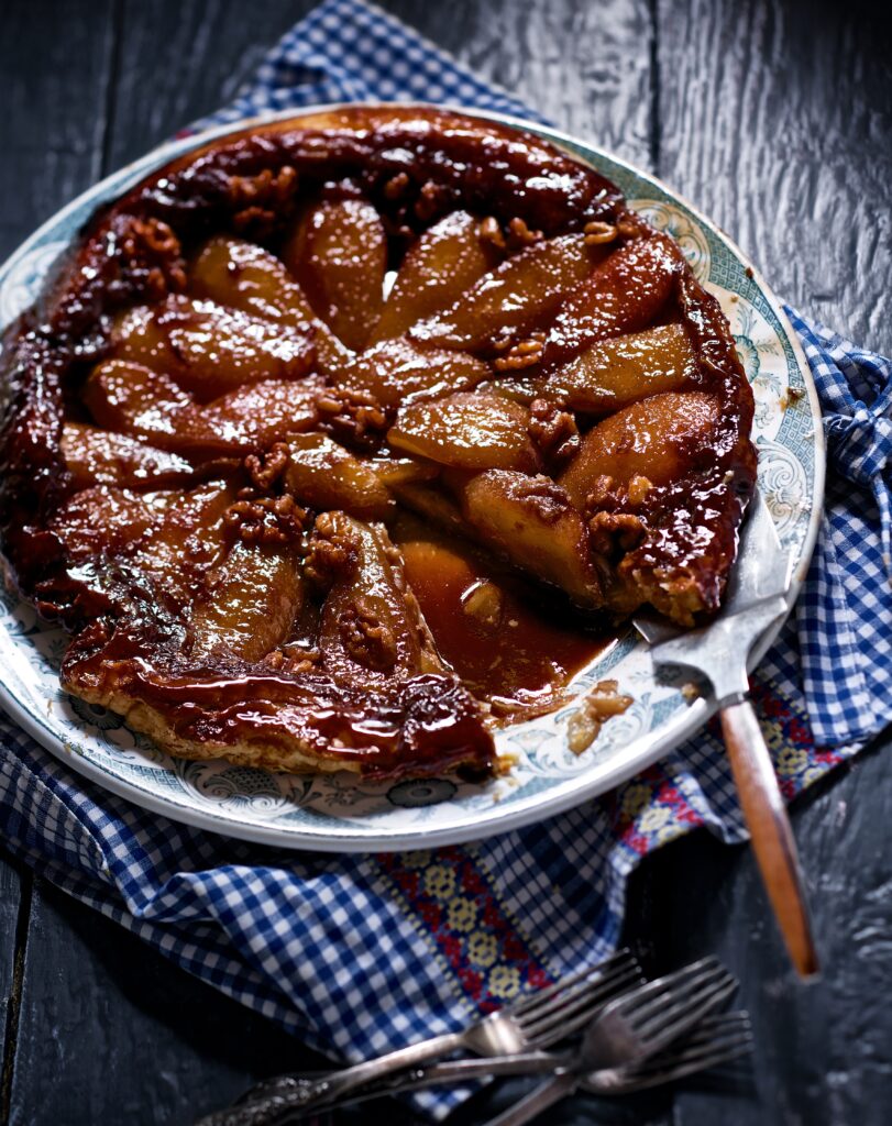 A pear crostata with maple syrup sitting on a pattern plate.