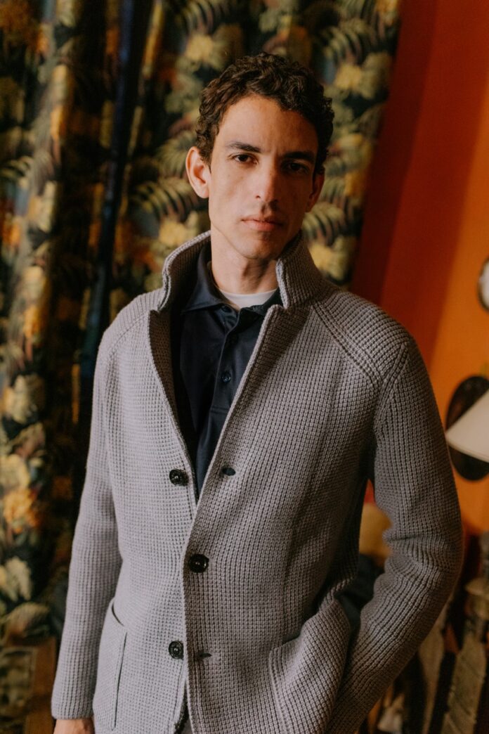 A stands in a grey fall cardigan.