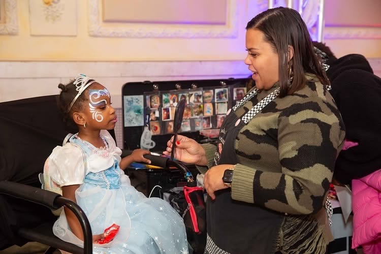 Face painter applies Halloween design to child at Pittsburgh family event.