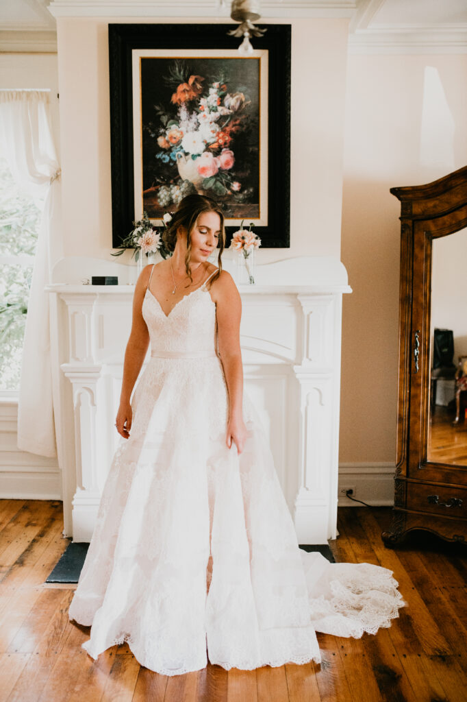 brides white dress in front of white fireplace and black flower painting