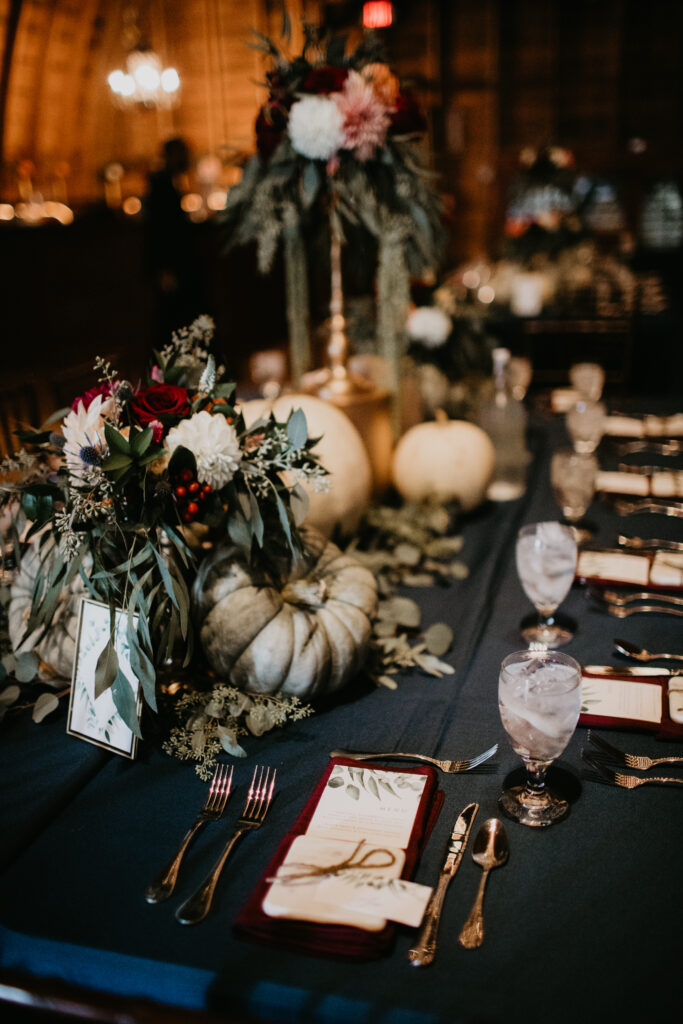 table set up with greens and dark red with white pumpkins