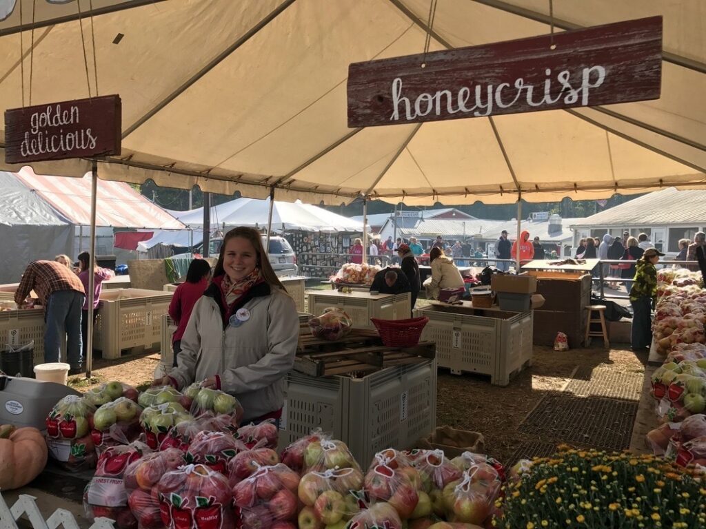 Woman at a Pittsburgh fall festival apple stand selling Honeycrisp apples