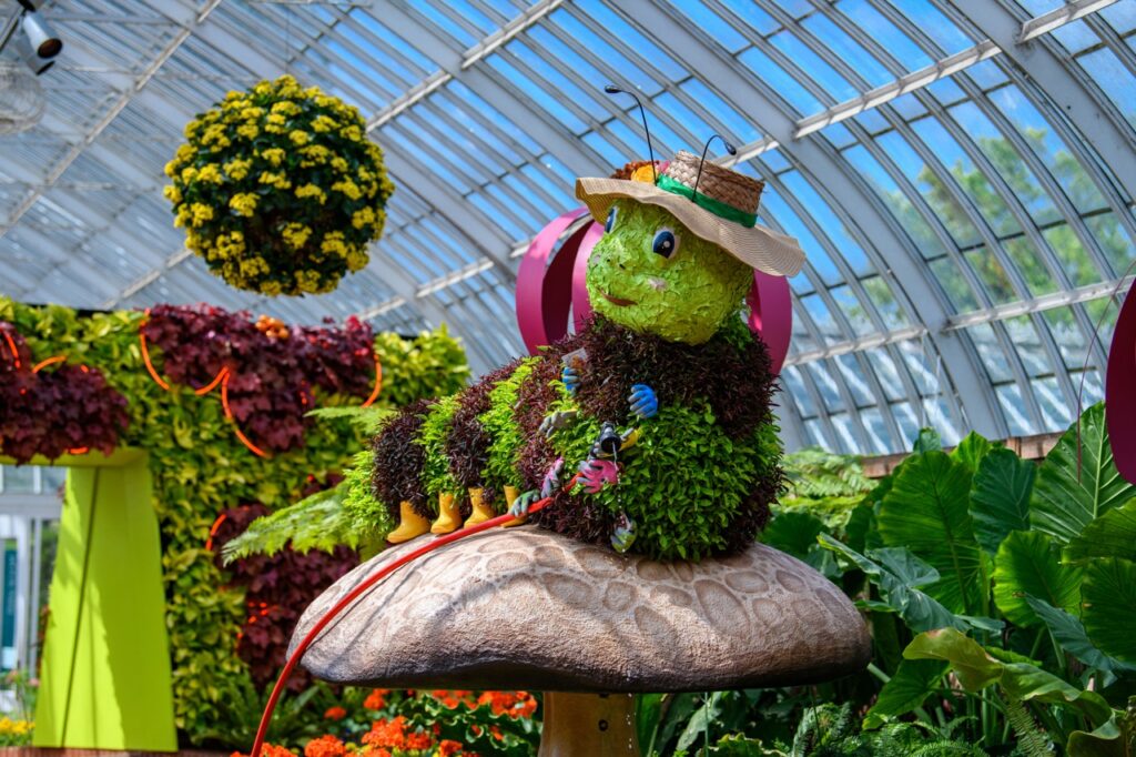 Whimsical caterpillar topiary at a Pittsburgh garden event, perfect for family Halloween fun.