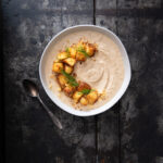 A cornbread soup sits in a bowl on a black table.