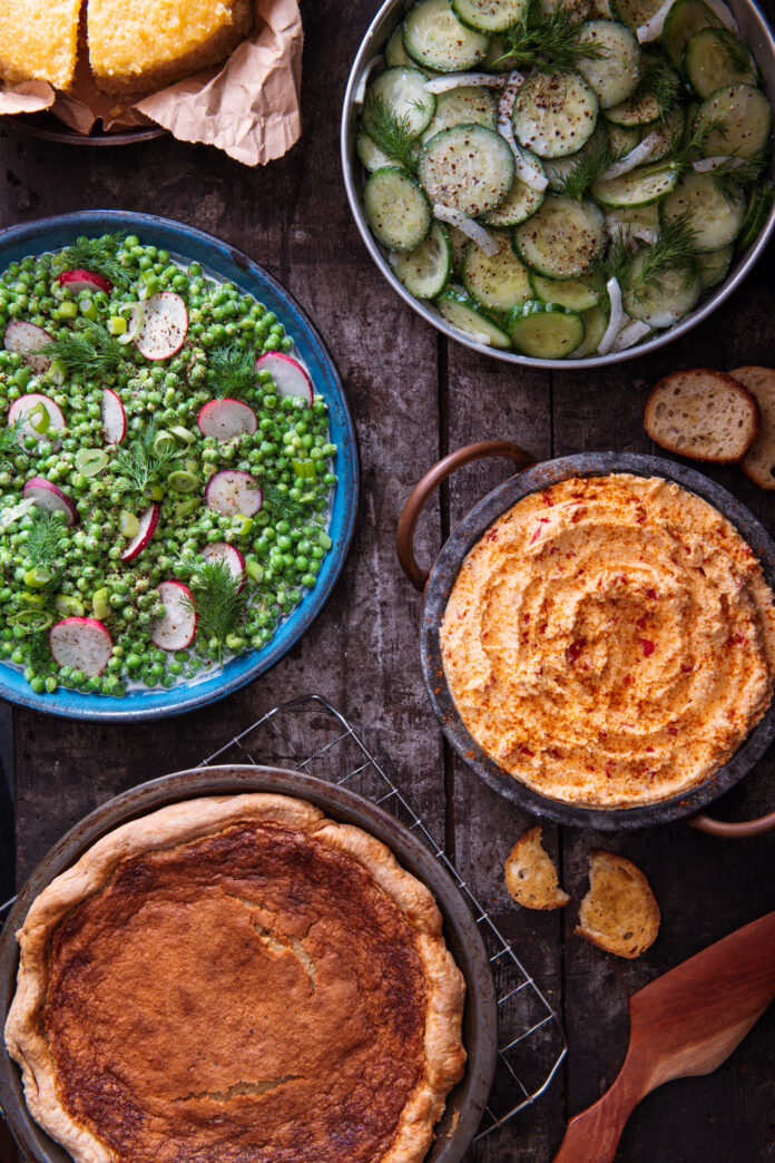 Four southern recipes sit on a picnic table from salad to dessert.