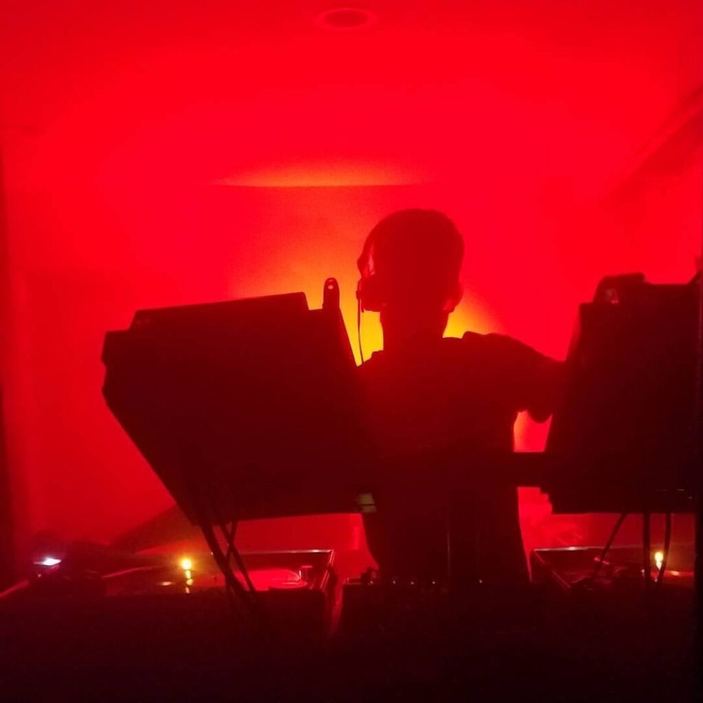A DJ performing under red lights.