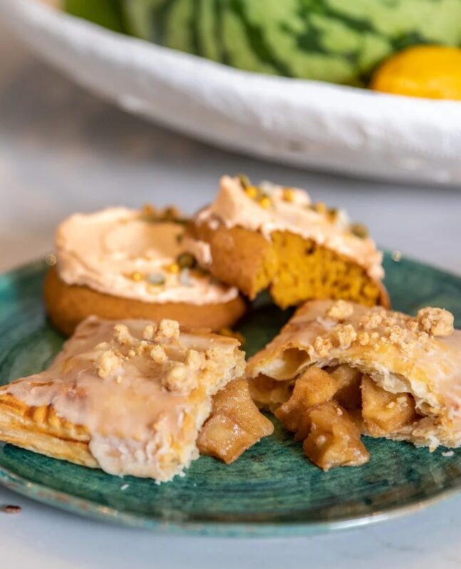 Homemade apple pie "pop-tarts" arranged in two rows on a textured baking sheet.