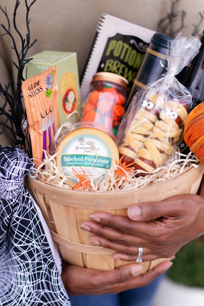 A woman holding a boo basket full of food items and little prizes.