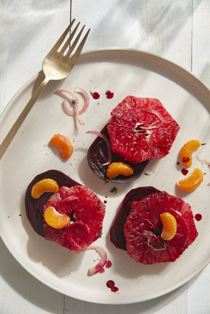 Braised Beet and Grapefruit Salad on a white plate with a steel fork at the corner