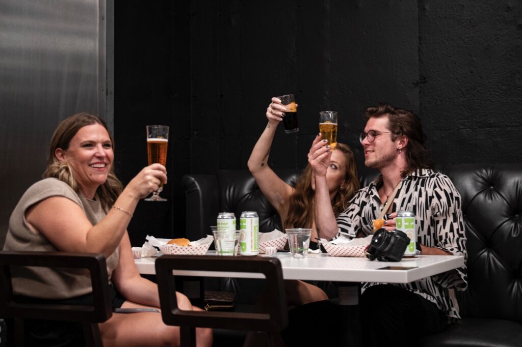 Three beer drinks look at their glasses while sitting at a table.