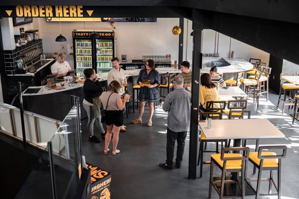 A group of people stand in a black and yellow dining area.