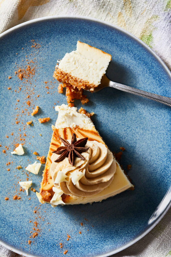 Caramel drizzle a top of a slice of caramel apple cheesecake, broken up on a blue plate.