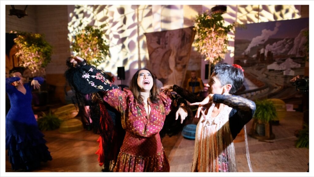 A birthday party guest of honor, Fadoua Loudiy, is happily shocked by a surprise performance of Flamenco dancers in red and blue ruffled dresses.