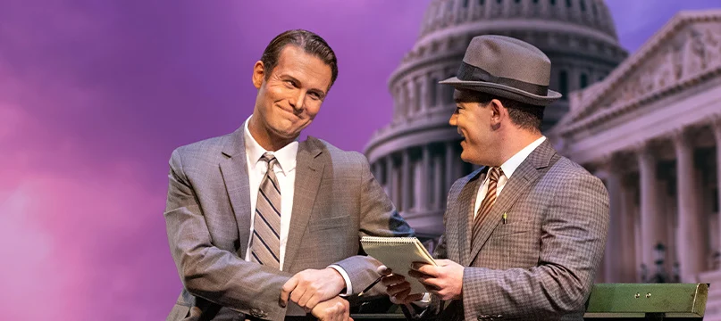 Fellow Travelers men on stage in suits shaking hands