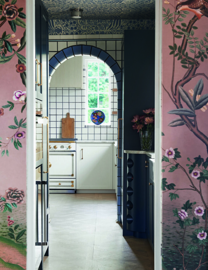 A pink wallpaper entry way leads to a white clean kitchen with white and black tiles.